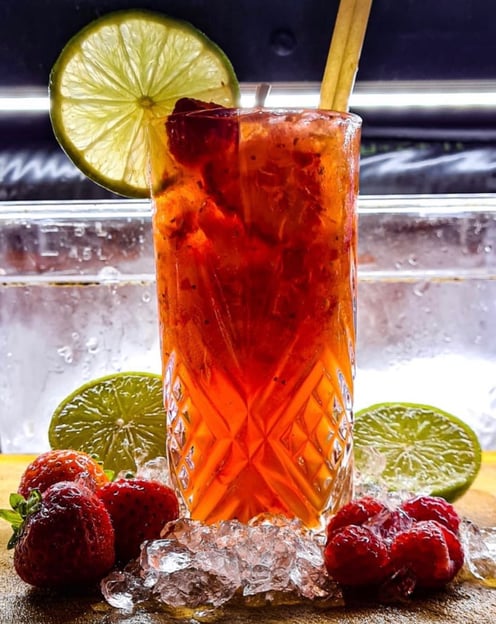 a glass of fruit juice with strawberries and lime
