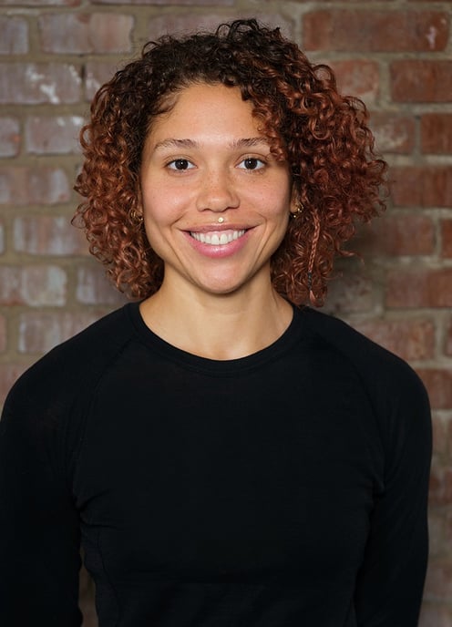 El, a Black bi-racial nonbinary psychotherapist with curly hair smiles into the camera