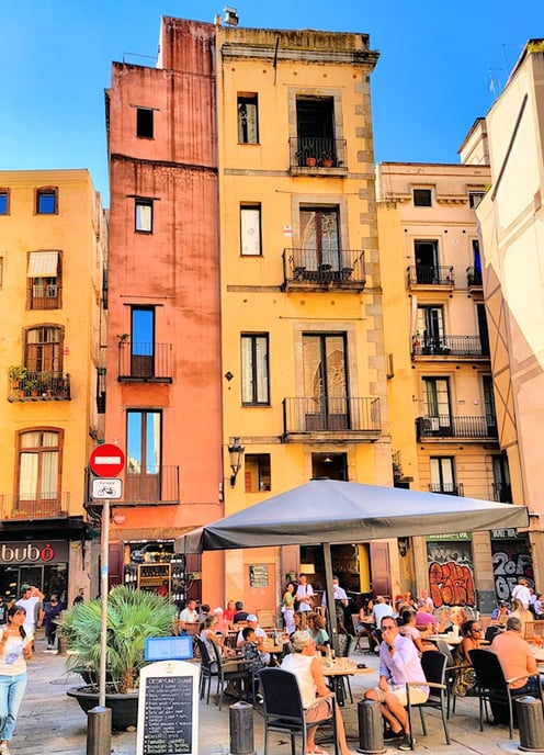 A busy medieval square with outdoor café in front of colorful old houses in Barcelona, Europe