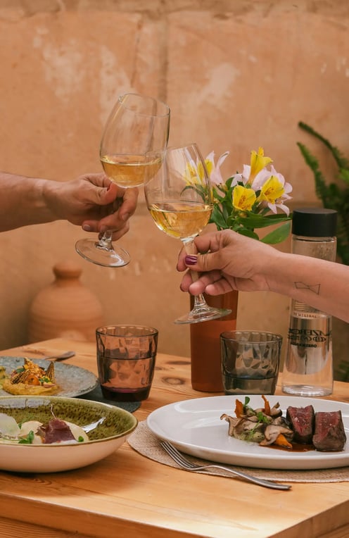 Dos copas brindan la comida que han pedido Es Mestral, se trata de solomillo, pescado fresco y unas alcachofas