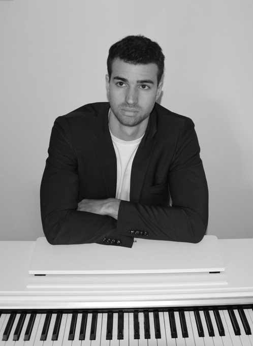 a man in a suit and tie sitting at a piano