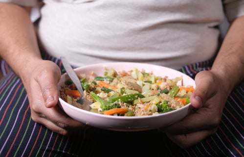 a person holding a bowl of food with a spoon and fork