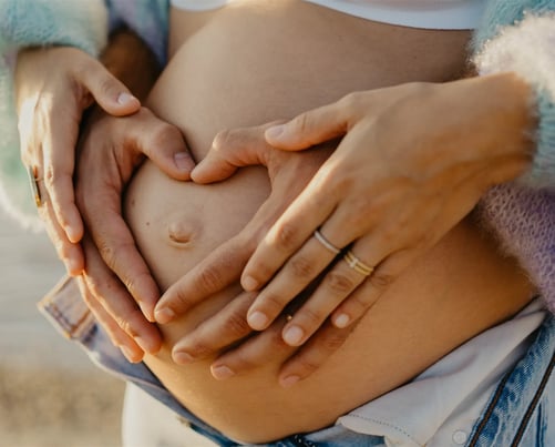 Mains des parents formant un cœur sur le ventre rond – photo de grossesse tendre dans le Gard