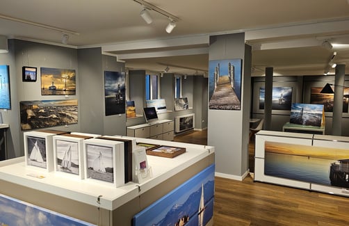 Fotogalerie – Innenraum mit ausgestellten Fotografien an den Wänden und auf Tischen