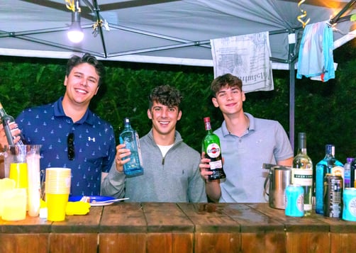 three men standing at a bar with drinks