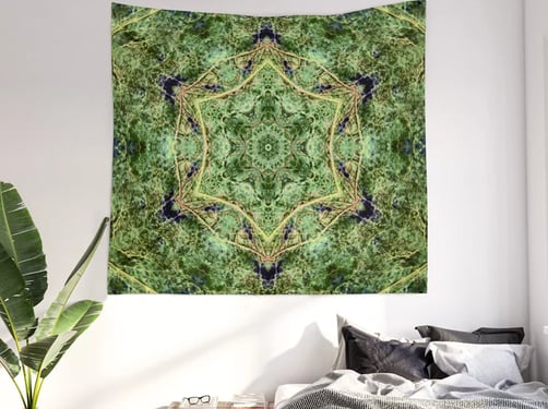 Tapestry on wall with bed underneath and a plant to the left of the bed