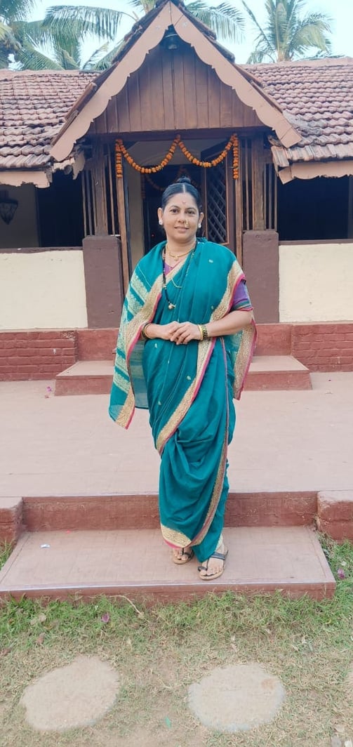 पारंपरिक साडीतील सवाष्ण, पारंपारिक घरासमोर उभी