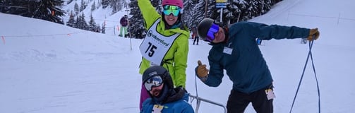 alt="Sean in his sit ski with Outdoors for All instructors Kristin and Ted, posing for the camera