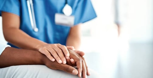 A nurse gently holds a patient's hand, providing comfort and support in a healthcare setting.