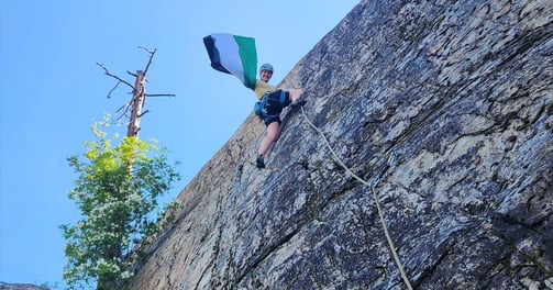 A climber halfway up the wall waving a Palestinian flag