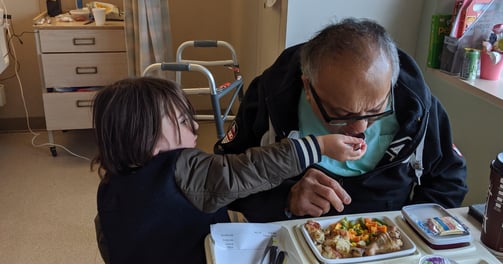 Zafira's  late father in the hospital, her young son feeds him