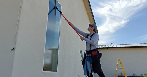 man washing tall exterior window pane