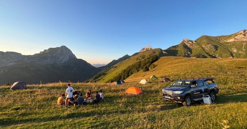 a truck parked in a grassy field with people sitting around