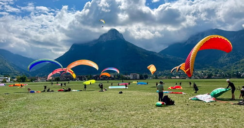 un groupe de personnes s'entraîne à gonfler leur parapente au sol