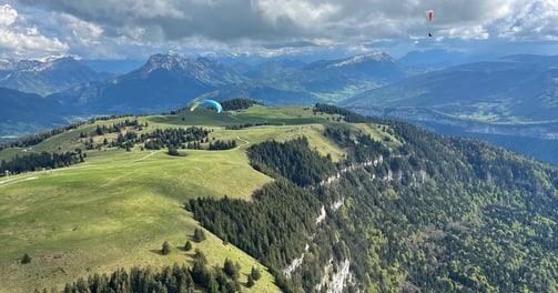 a person parasailing over a mountain range