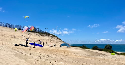 Plusieurs personnes s'entraînent à gonfler leurs parapentes sur la plage. 