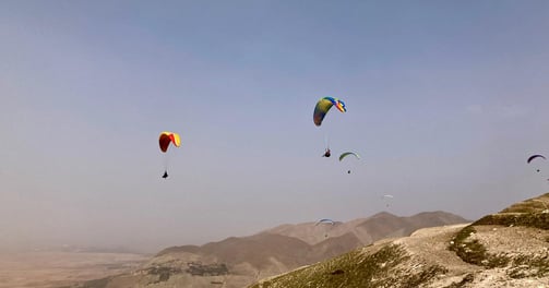 Plusieurs parapentes volent au dessus des dunes du sud du Maroc