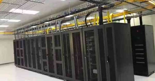 a large machien room with yellow fiber cable trays and wire mesh cable trays
