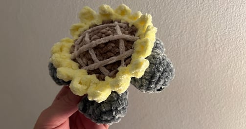 a person holding a crochet flower in their hand