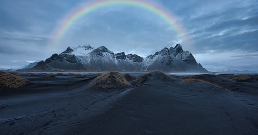 a rainbow - colored rainbow over a mountain range