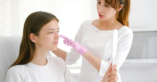 a woman in a white shirt is getting her skin consultation