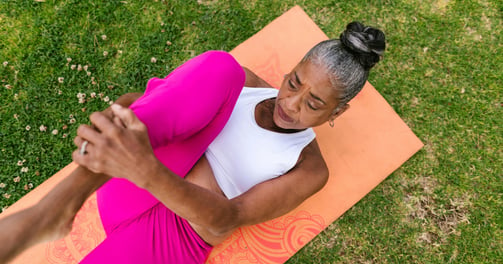 elderly adult female stretching on a yoga mat