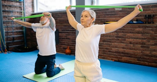 elderly adult male and female exercising with bands