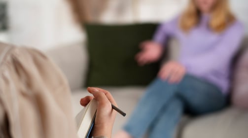 Foto de psicóloga e paciente mulher em consultório de psicologia.