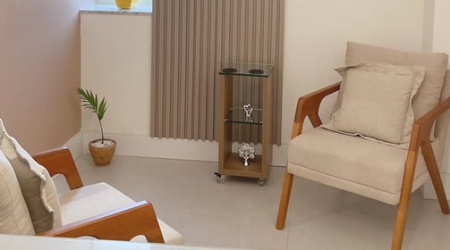 Foto do consultório de psicologia da psicóloga Laura Maria, duas poltronas e fundo de madeira.