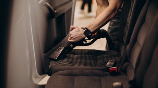 Nettoyage de la banquette arrière d'une voiture avec un aspirateur.