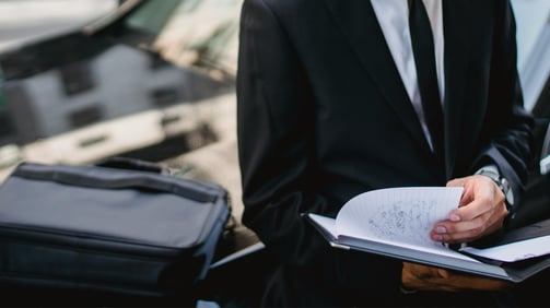 Expert assis sur le capot de sa voiture, travaillant pour aider ses clients à vendre leur véhicule.