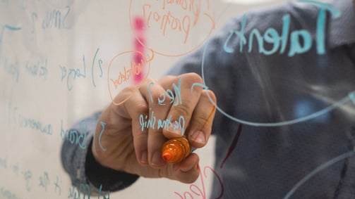 image of man writing on board by kvalifik from unsplash