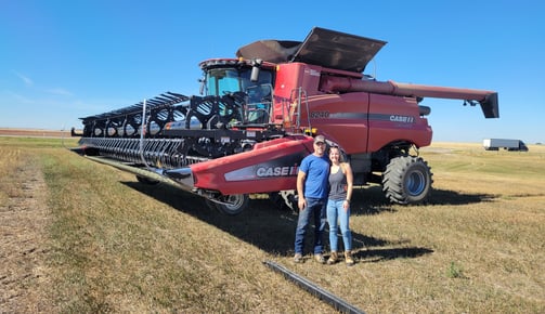 Ashley and her dad standing in front of a Case combine