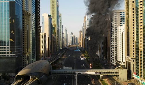 a city street with black smoke billowing through the air