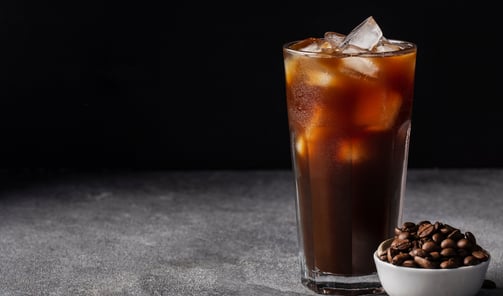 a glass of iced coffee with coffee beans