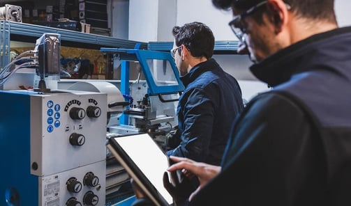 Pracownicy fabryki produkują części metalowe używając maszyny cnc