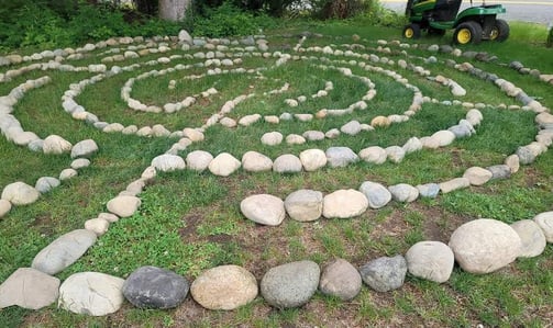 a circular stone labyrinth maze on green grass