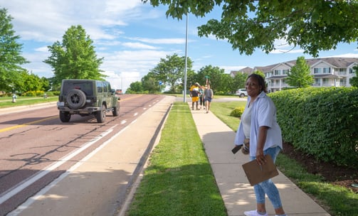 Full-body shot of Sophia Smith walking down a sidewalk with a clipboard in hand