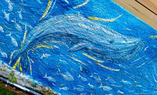 détail d'une peinture murale représentant une baleine et un banc de poissons