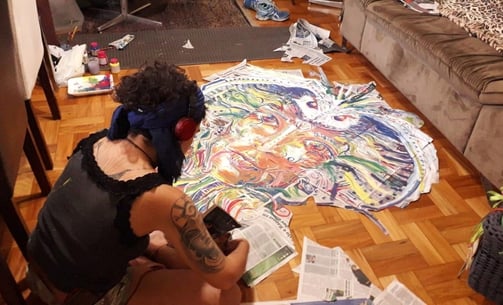 Naía découpe la composition réalisée sur papier journal avant d'aller la coller dans les rues de Belo Horizonte