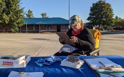 Person in a wheelchair filling out a survey at a table stationed to conduct surveys
