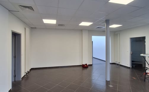 Une photo avant transformation de l'ancien showroom avec des murs blanc et un sol gris
