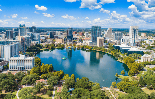 a city skyline view of a lake and a boat in the water in orlando