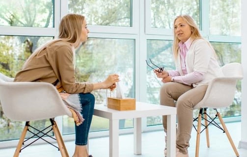 two women sitting at a table with a cup of coffee