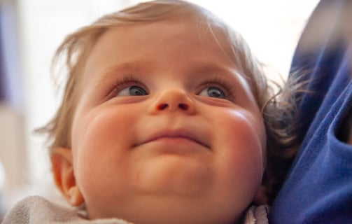 a baby is smiling and looking up her mom