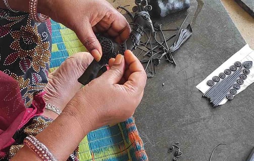"Tribal artisan shaping wax mold to cast brass idol in traditional lost-wax method"