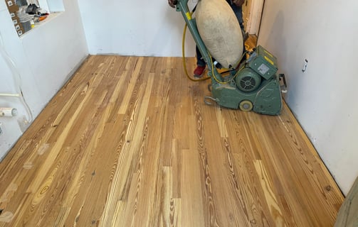 a man in a black jacket is using a machine to remove wood floors