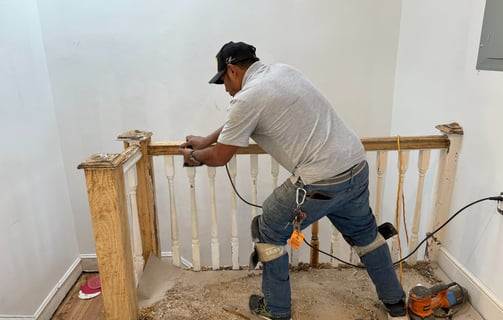 a man in a white shirt and jeans standing on a stair rail