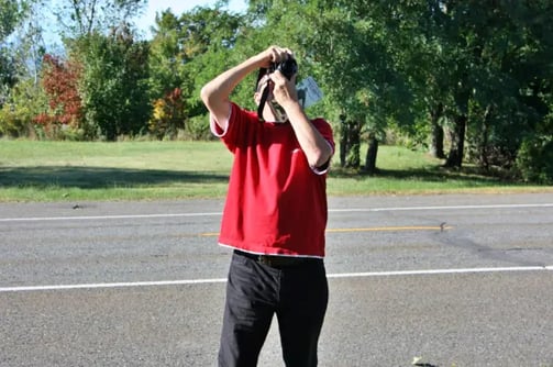 Homme avec t-shirt rouge prenant une photo.