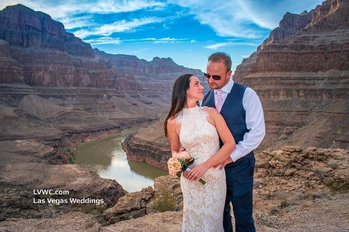 a man and woman standing on a cliff overlooking a river